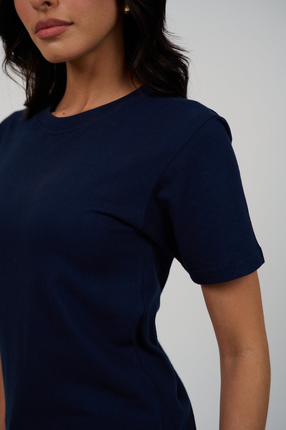 Navy blue t-shirt worn by a person on a plain background