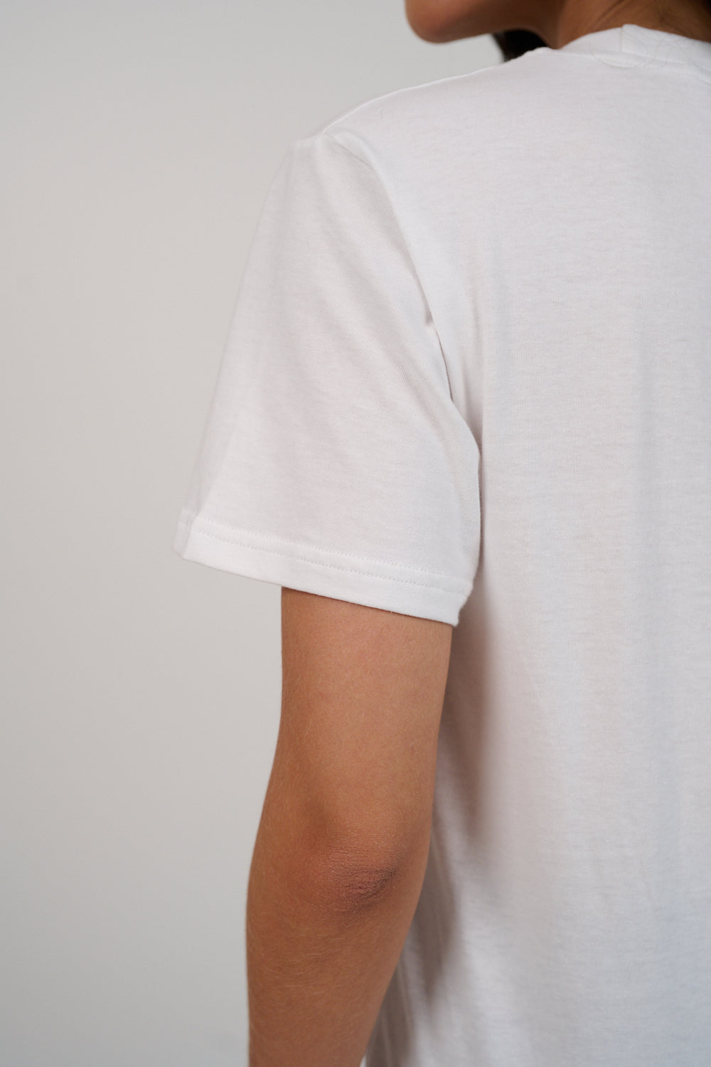 White t-shirt worn by a person on a plain background