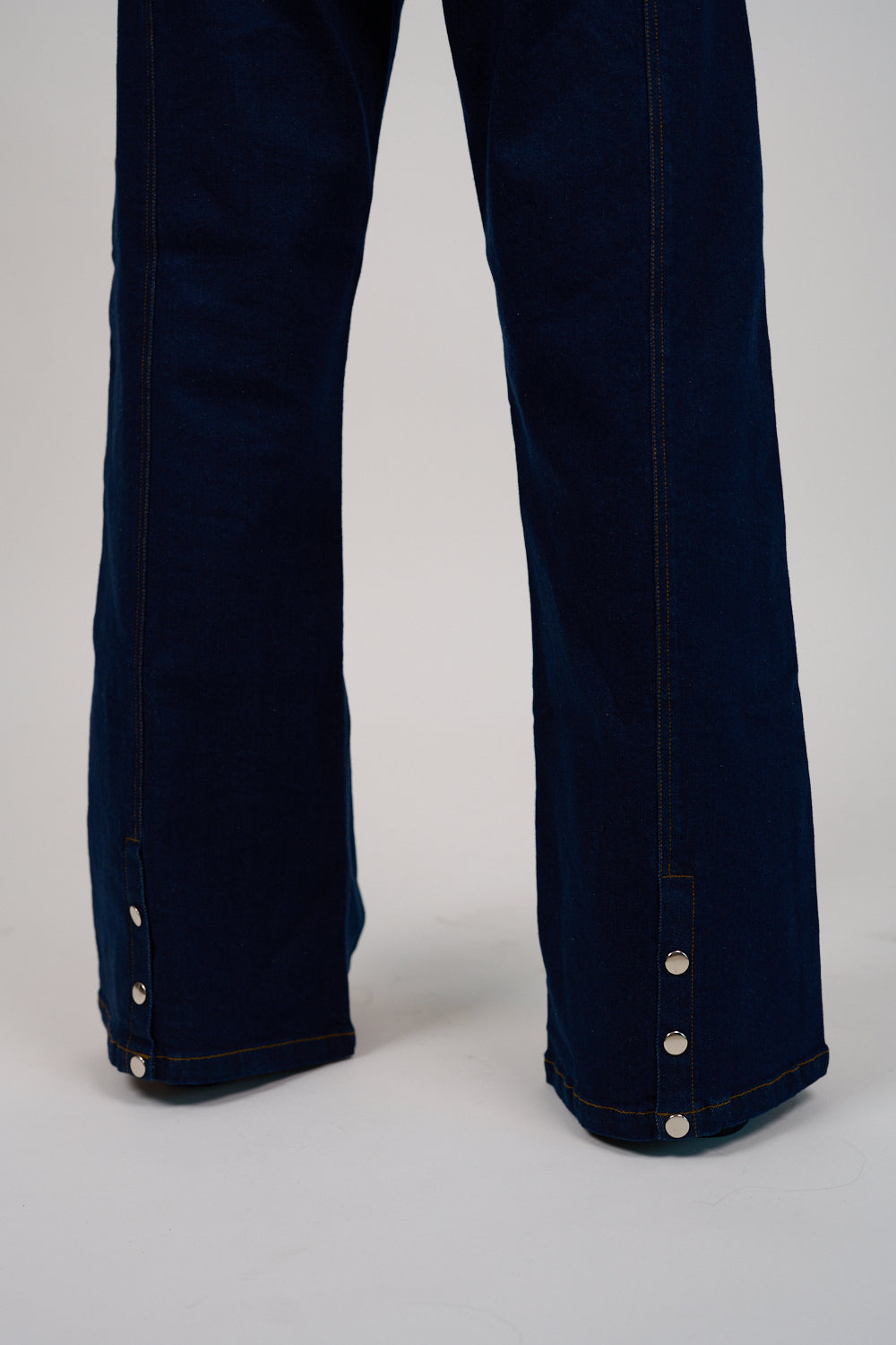 Navy blue jeans with white buttons on a light gray background