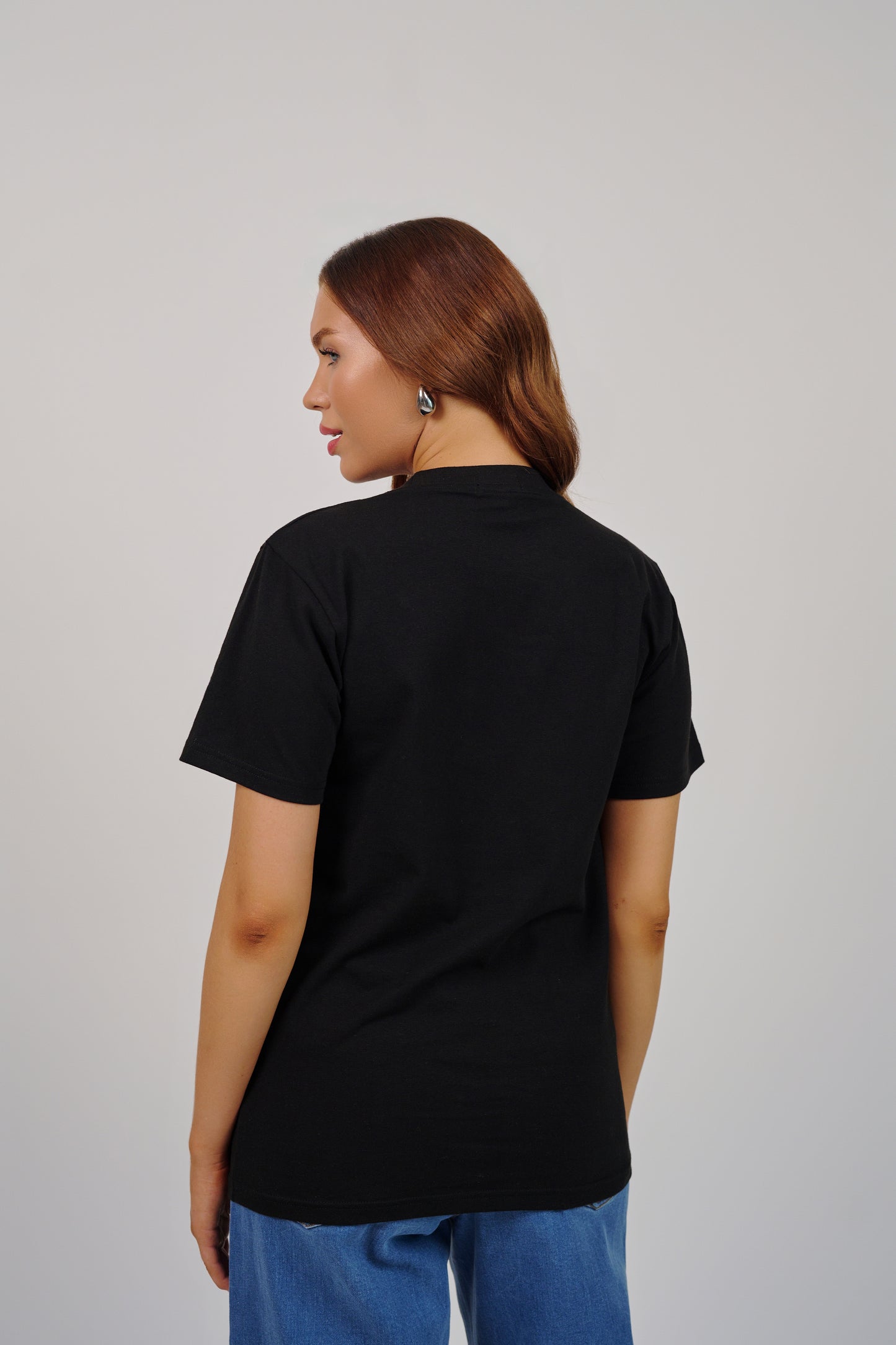 Person wearing a black t-shirt and blue pants on a plain background