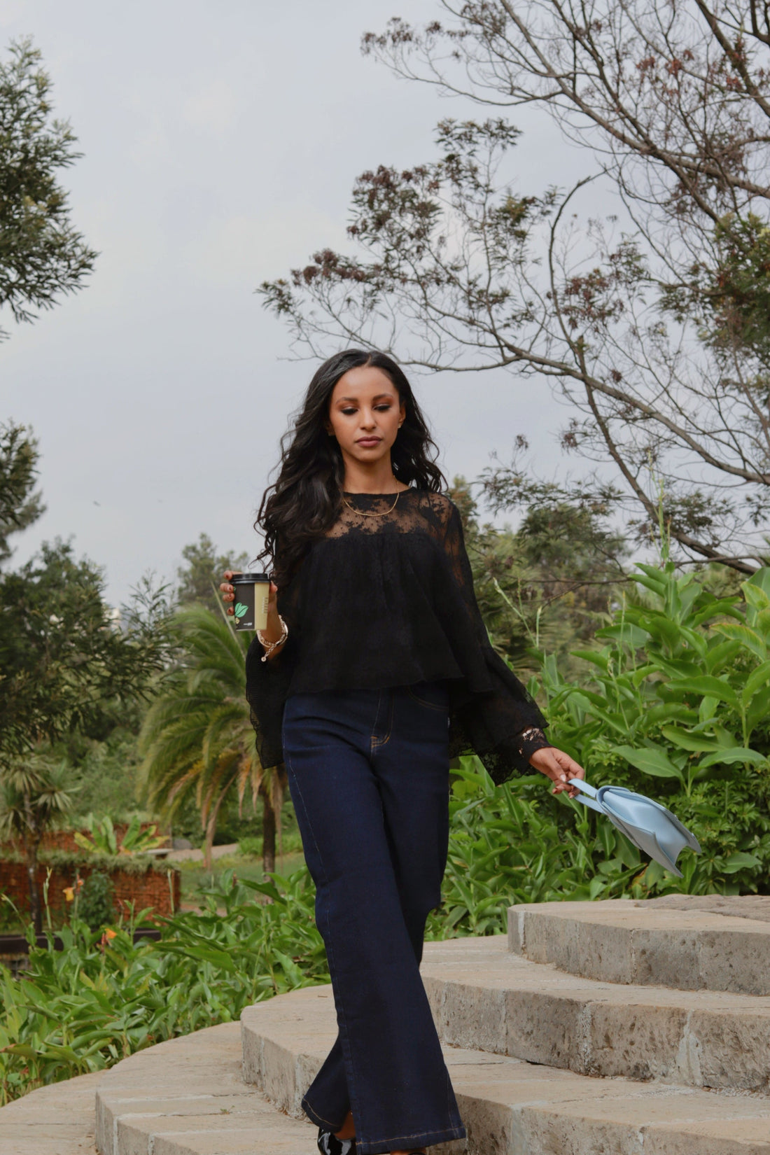 women wearing ENKU Jeans holding coffee and walking in the park