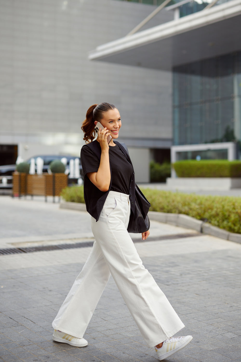 Woman walking outdoors on a city street, talking on a phone.