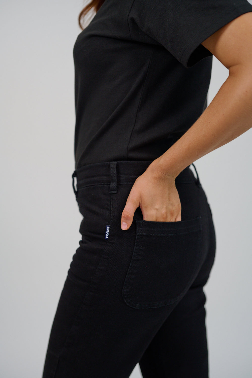 Person wearing black pants with a visible brand logo on a plain background
