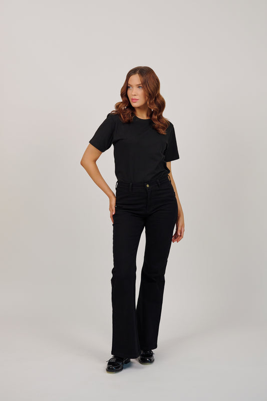 Woman wearing a black t-shirt and black pants on a gray background