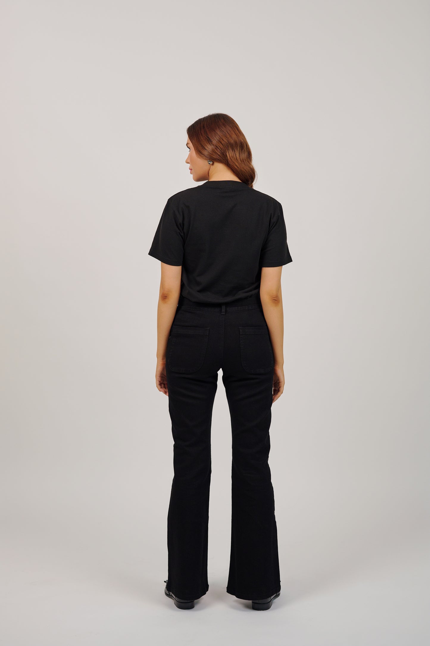 Person wearing a black t-shirt and black flared pants on a white background