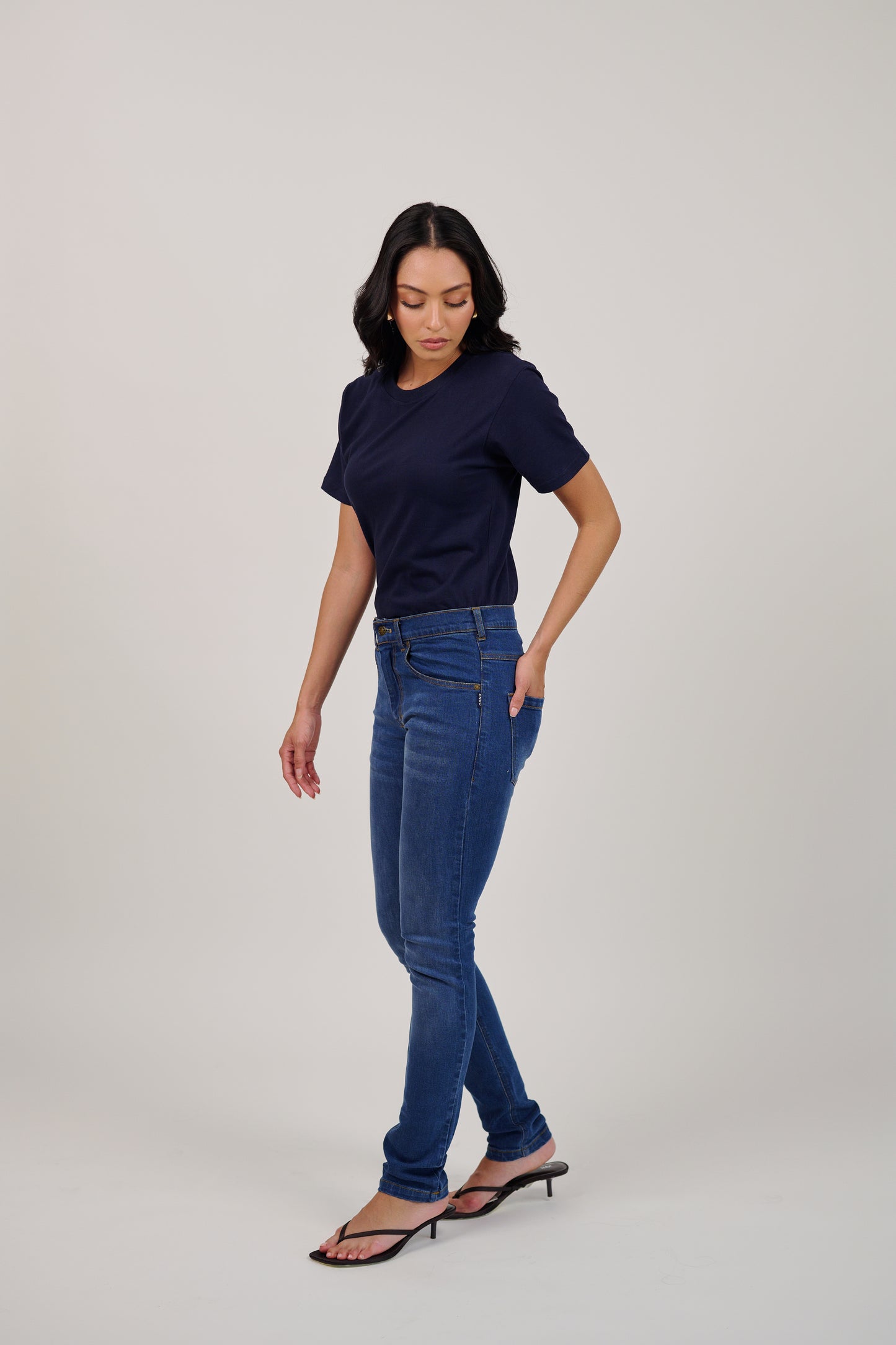 Woman wearing a navy t-shirt and blue jeans on a white background