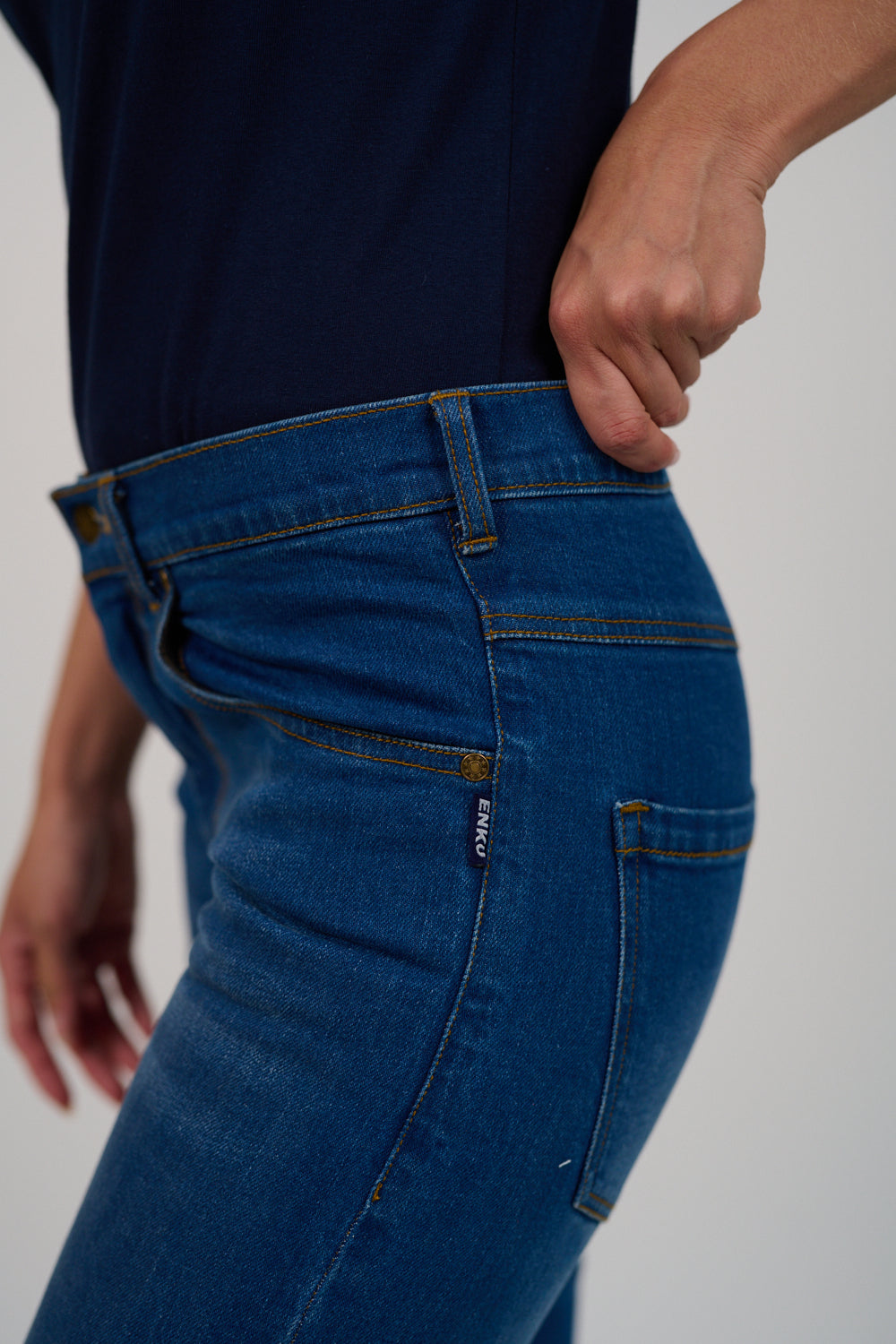 Person wearing blue jeans with a plain background