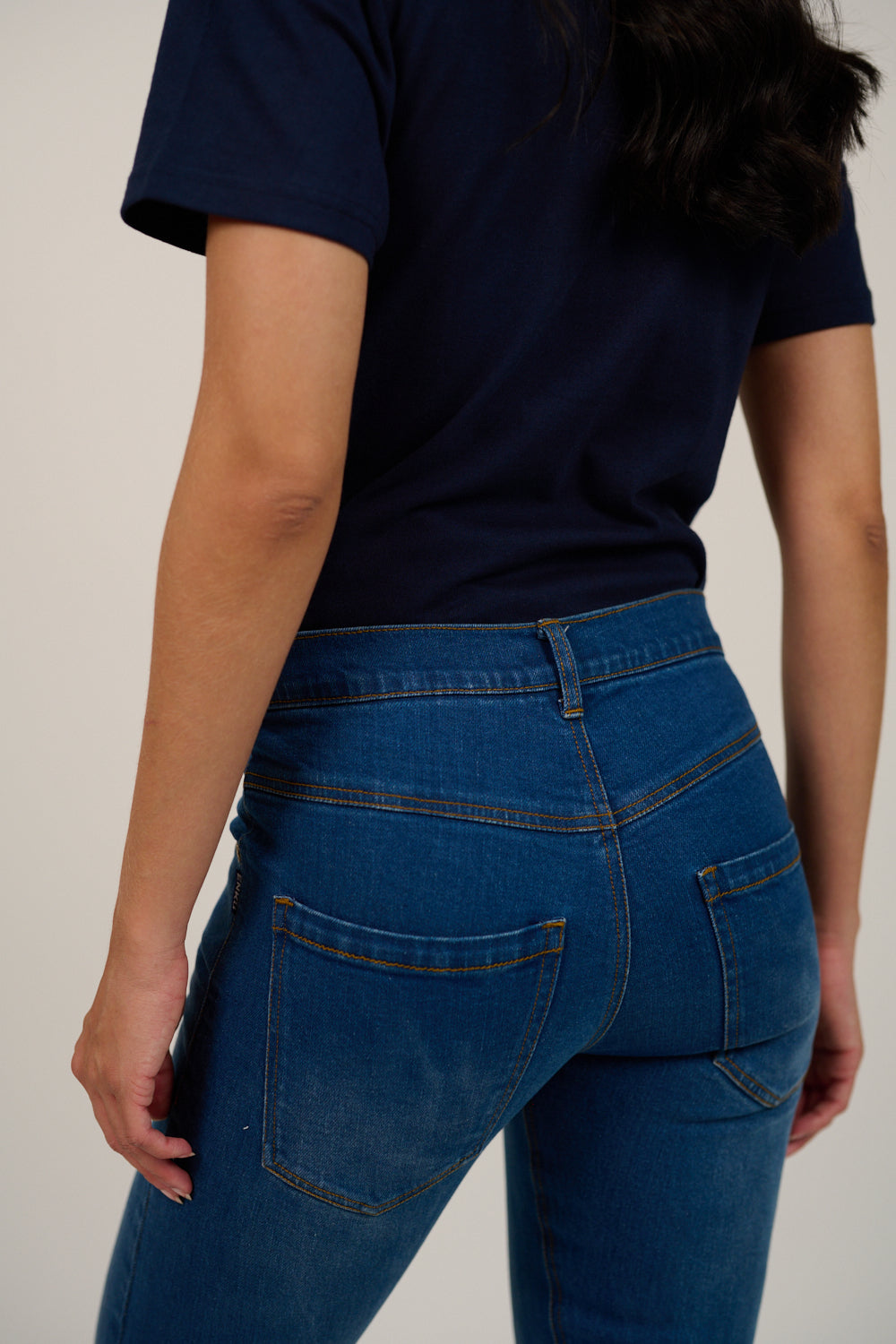 Person wearing a navy blue t-shirt and blue jeans on a plain background