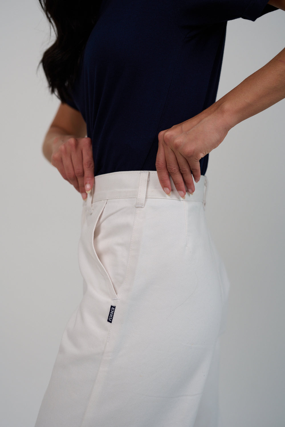 Person wearing a navy top and white pants on a plain background