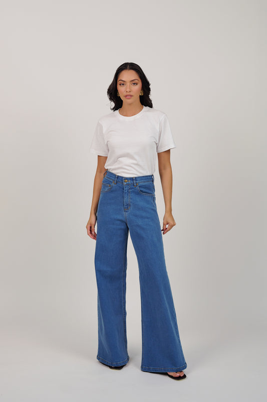 Woman wearing a white t-shirt and blue jeans on a plain background