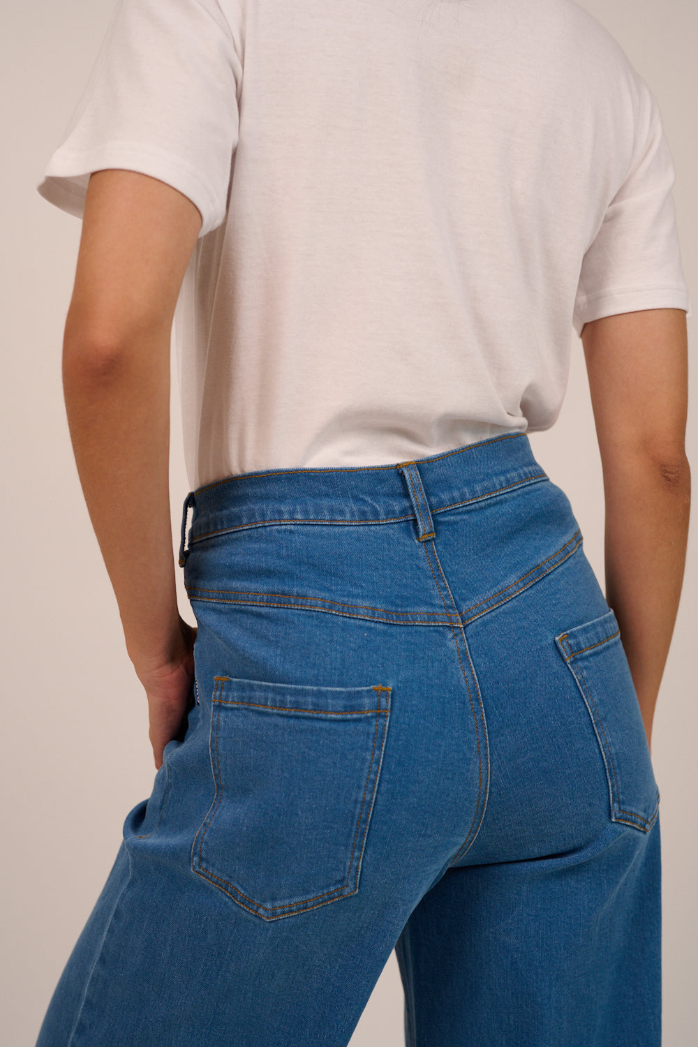 Person wearing blue jeans and a white t-shirt on a plain background