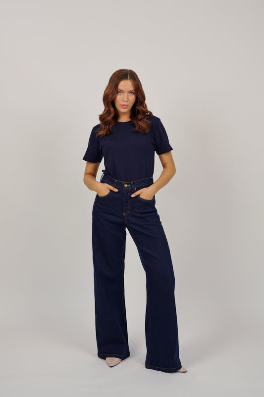Woman wearing a navy blue t-shirt and jeans on a white background