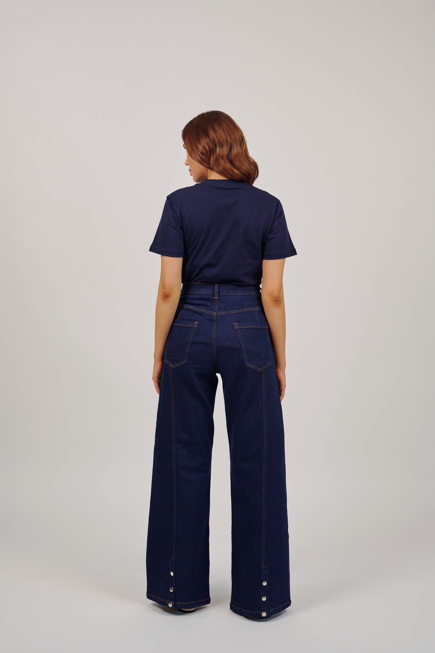 Person wearing a navy blue shirt and wide-leg jeans on a light gray background
