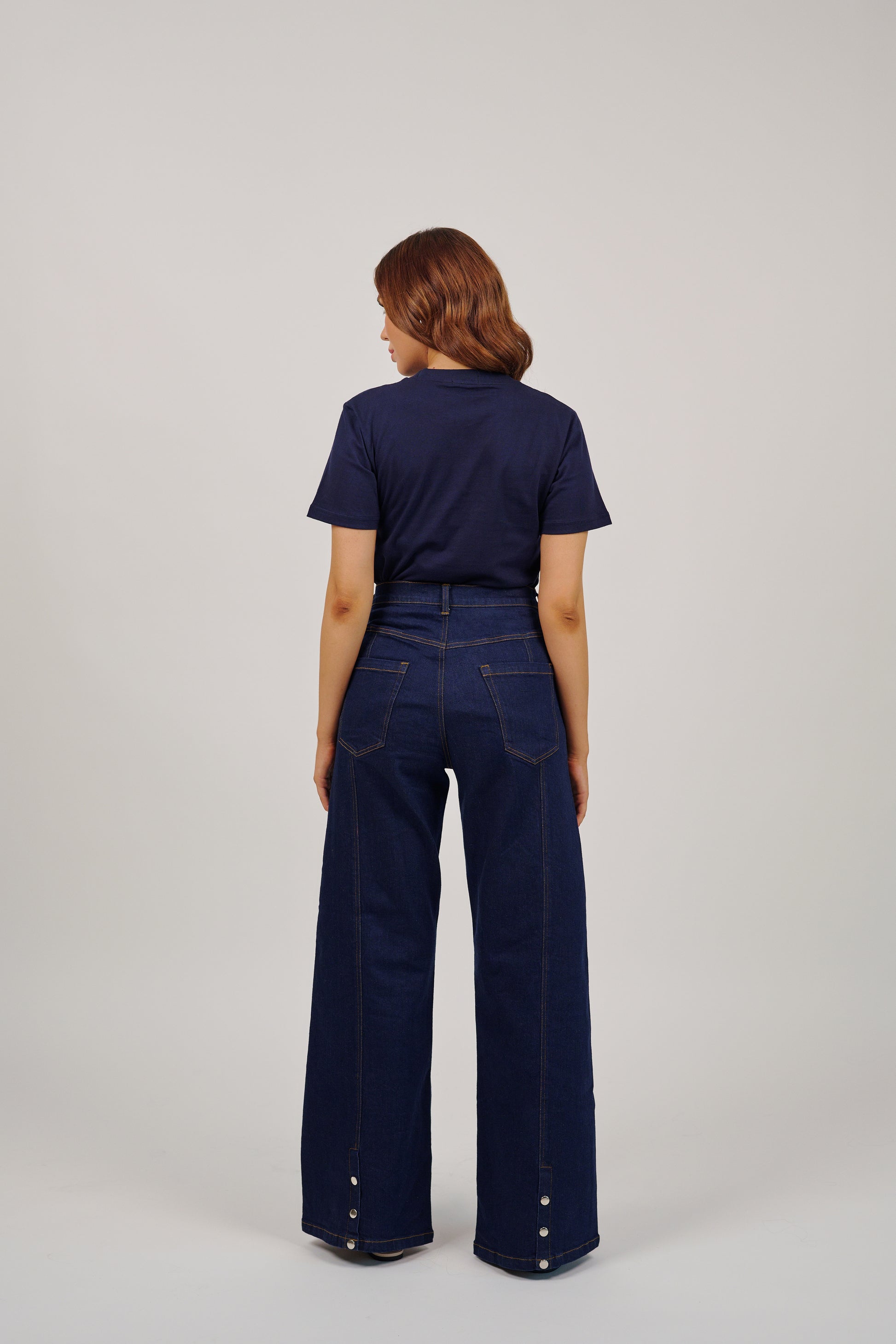Person wearing a navy blue shirt and wide-leg jeans on a light gray background