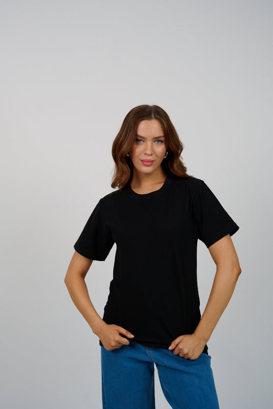 Woman wearing a black t-shirt and blue pants against a gray background